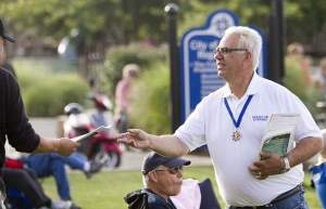Dennis Dimoff hands out fliers with the schedule of the season for the Brighton Kiwanis Gazebo Concerts. Dimoff has been running the concerts for decades with the Kiwanis. / GILLIS BENEDICT/DAILY PRESS & ARGUS